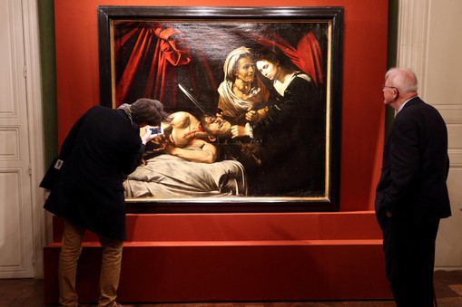 Visitors looks at a painting entitled Judith Beheading Holofernes during its presentation in Paris