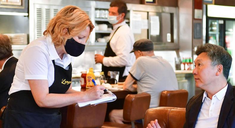 A waitress takes an order from a customer at the reopening of Langer's Delicatessen-Restaurant in Los Angeles on June 15, 2021.
