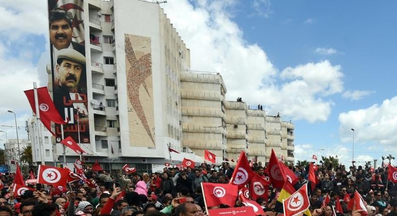 Tunisians wave their national flag during a march against terrorism outside Tunis' Bardo Museum on March 29, 2015