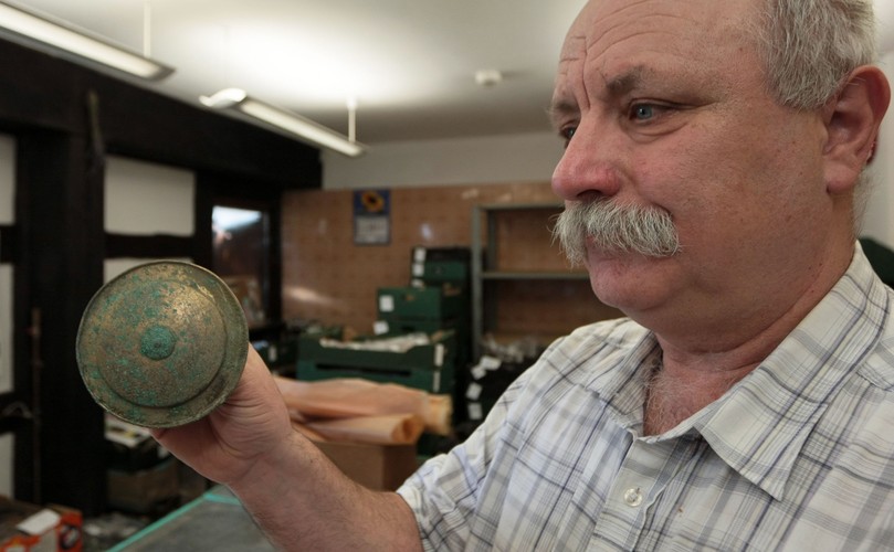 Stanisław Sinkowski z Muzeum Lubuskiego im. Jana Dekerta w Gorzowie Wielkopolskim prezentuje guz ozdobny z brązu