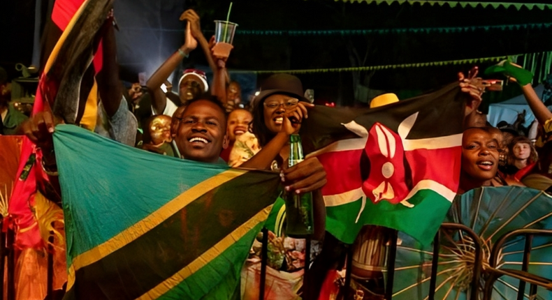 Festival-goers wave flags of Tanzania and Kenya. (Photo by BADRU KATUMBA / AFP)