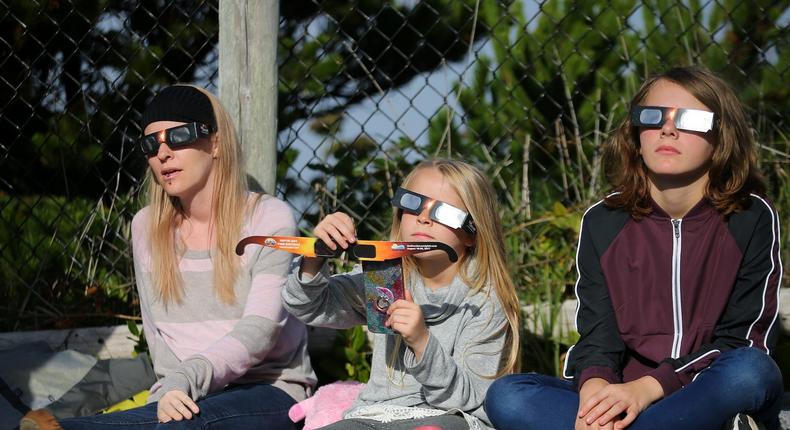 People use solar viewing glasses as the sun emerges through fog cover before the solar eclipse in Oregon.Mike Blake/Reuters