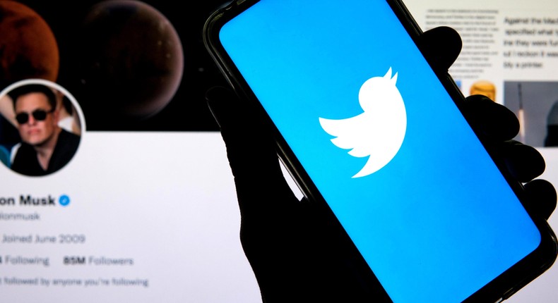 The Twitter logo seen displayed on a smartphone with Elon Musk's account in the background.