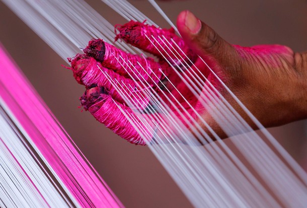 A worker applies colour to strings which will be used to make kites, alongside a road in Ahmedabad