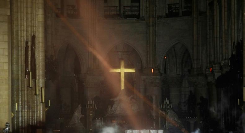 Smoke rises around the alter in front of the cross inside the Notre-Dame Cathedral in Paris as firefighters continued to extinguish the blaze on Tuesday