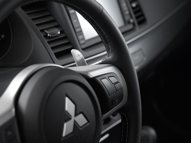 Galerię
Za wielką paszczą rekina czai się, znany z evo, dwulitrowy silnik tyle że pogania go mniejsza turbina, dlatego zdławiony motor
daje 240 KM (zamiast 295 KM). Mniejsza siła w połączeniu z dwusprzęgłową skrzynią Twin Clutch SST sprawia, że auto od pierwszego kopnięcia gazu zdaje się mniej narowiste niż wyczynowy brat. Co nie oznacza, że ospałe - po prostu moc jest uwalniana bardziej równomiernie. Ralliart w 7 sekund teleportuje się poza granicę 100 km/h, (evo potrzebuje 6,3 s).

>>>Mitsubishi na prąd elektryzuje Polaków!

Zautomatyzowana przekładnia ma dwa tryby pracy - normalny i sportowy. W porównaniu do bardziej zaawansowanej skrzyni evo brakuje trybu super sport (nazwa mówi sama za siebie) ale i tak jest dobrze…