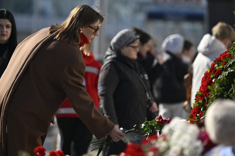 Ludzie składają kwiaty i zapalają znicze pod salą koncertową Crocus City Hall, gdzie doszło do ataku terrorystycznego, w którym zginęło 146 osób, Rosja, 27 marca 2024 r.
