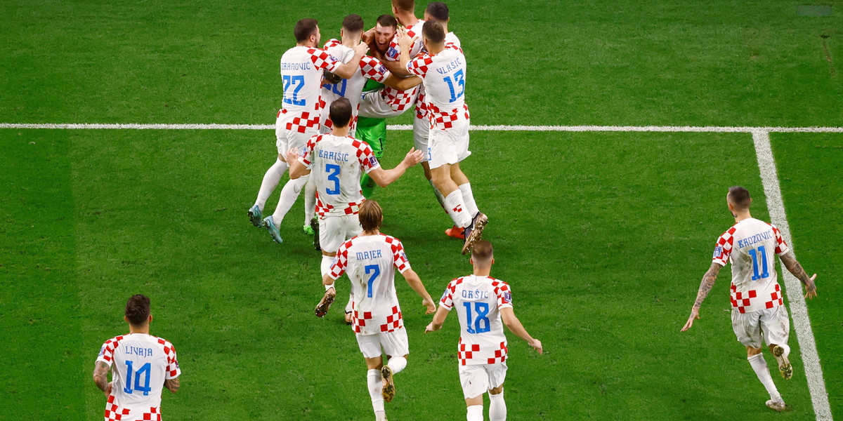 Dominik Livakovic tonie w objęciach kolegów, po tym jak zapewnił Chorwaci awans do ćwierćfinału mistrzostw świata