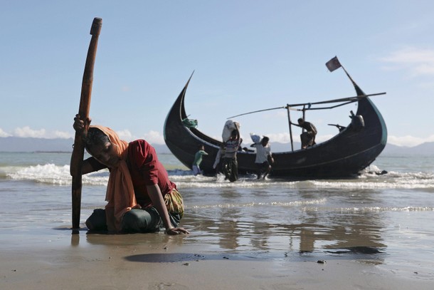 A woman collapses from exhaustion as Rohingya refugees arrive by a wooden boat from Myanmar to the s