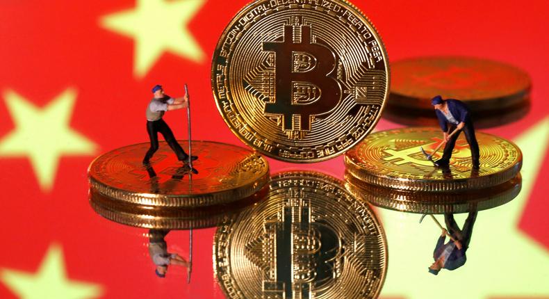 FILE PHOTO: Small toy figurines are seen on representations of the Bitcoin virtual currency displayed in front of an image of China's flag in this illustration picture, April 9, 2019. REUTERS/Dado Ruvic/Illustration