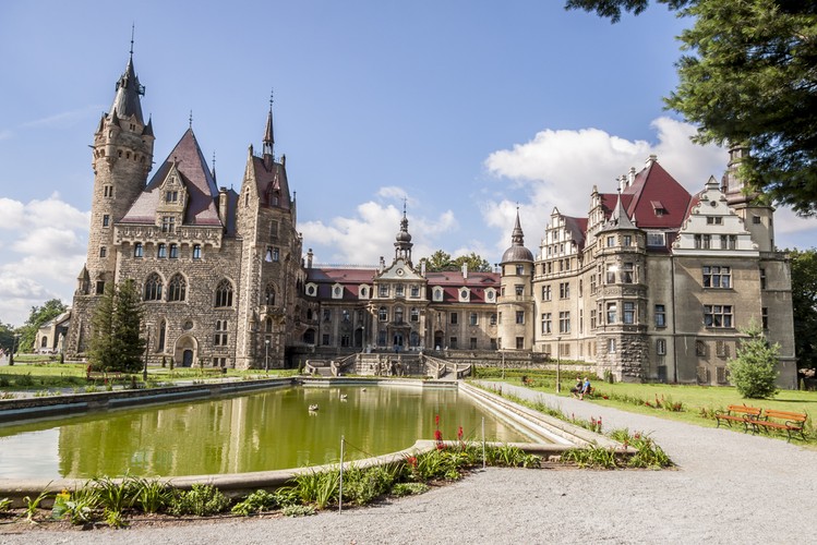 1. Moszna. Zamek w Mosznej, w województwie opolskim, to widok zapierający dech w piersiach. Pierwsza myśl jaką budzi to Harry Potter i szkoła czarodziei. To perełka architektury, pięknie i ze smakiem odrestaurowana, w której majestatyczne i przestrzenne komnaty urządzone w królewskim stylu czekają na gości. Zamek posiada 99 wież i 365 pomieszczeń, otacza go rozległy park z kilkusetletnimi dębami i lipami. Jedna z legend głosi, że w miejscu, w którym stoi niegdyś swoją siedzibę miał Zakon Templariuszy. Zamek można nie tylko zwiedzać, można również w nim spać. W swojej bogatej ofercie posiada przepiękne apartamenty i odnowę bilogiczną, a także nietuzinkowe atrakcje dla najmłodszych, jak choćby letnia szkoła magii i czarodziejstwa, inspirowana przygodami Harry’ego Pottera, Hermiony Granger i Rona Weasley’a. To trzeba zobaczyć!