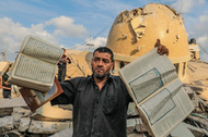 A man holds books of the Quran in front of a mosque destroyed by Israeli airstrikes.