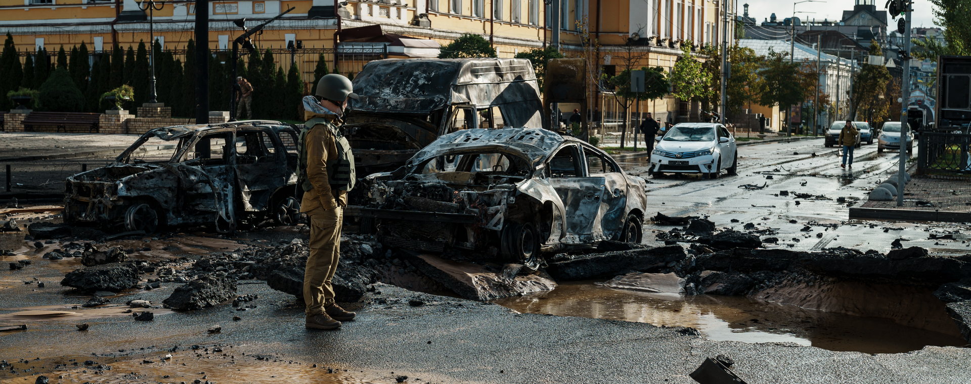 Krater po rosyjskim pocisku i wraki pojazdów zniszczonych przez ostrzał w Kijowie w Ukrainie. 10 października 2022 r. 