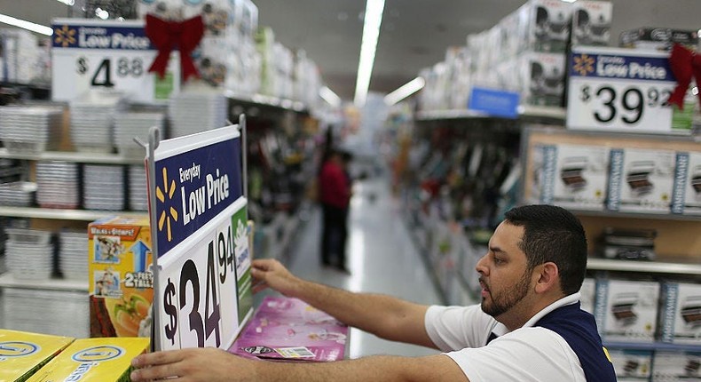 A Walmart employee adjusts a sign listing prices.