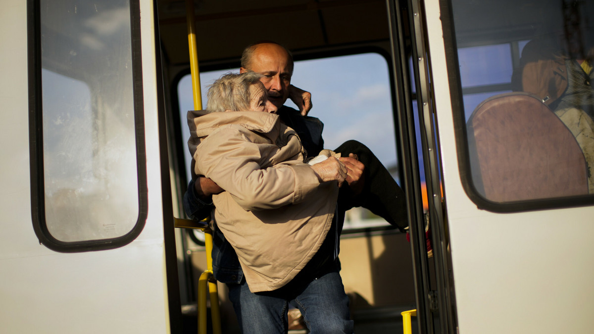 Kobieta jest wynoszona z autobusu, którym przyjechali do ośrodka dla przesiedleńców w Zaporożu uciekinierzy z Mariupola, Tokmaku i Berdiańska.