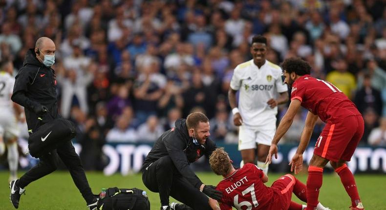 A trainer runs on the pitch to help Liverpool's Harvey Elliott (C) Creator: Oli SCARFF