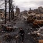 A man pushes his bike through debris and destroyed Russian military vehicles on a street on April 06, 2022 in Bucha, Ukraine.