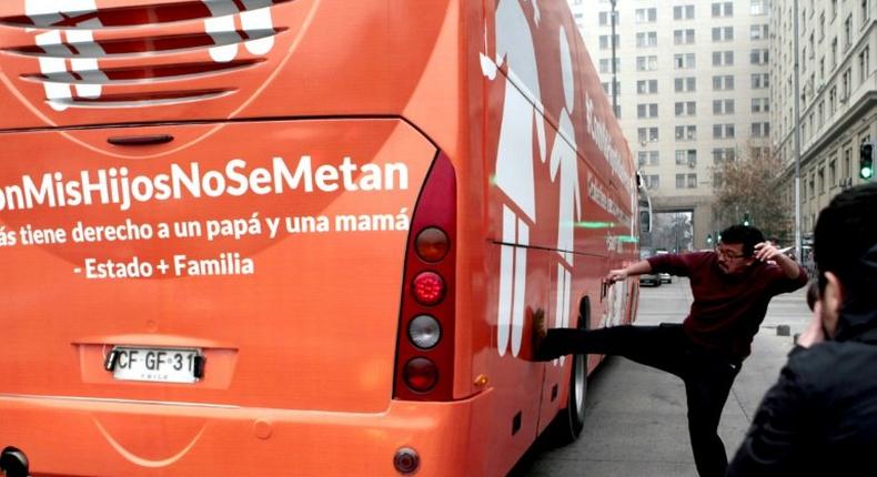 A pro-choice activist kicks the bus chartered by a conservative group opposed to gay rights in Chile's capital July 10, 2017.