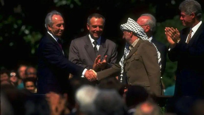 Lider PLO Jaser Arafat (desno) rukuje se sa izraelskim ministrom spoljnih poslova Šimonom Peresom na potpisivanju Sporazuma iz Osla dok američki predsednik Bil Klinton (krajnje desno) aplaudira | Foto: Getty Images