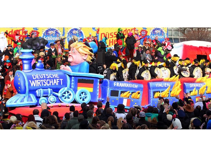 Angela Merkel pędzi płonącym pociągiem z nazwami krajów w kryzysie na paradzie w Dusseldorfie