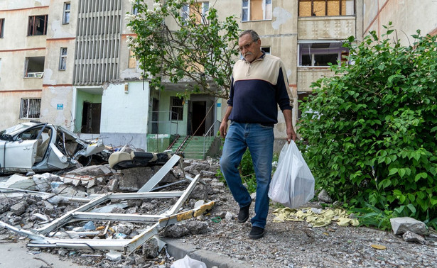 Jeden z mieszkańców przed zniszczonym blokiem mieszkalnym w Charkowie