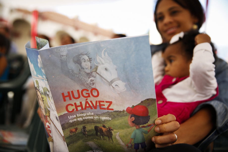 A woman holds a story book about the late Venezuelan President Hugo Chavez during a writing workshop at the 4F military fort in Caracas, December 14, 2014.