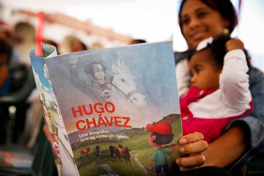 A woman holds a story book about the late Venezuelan President Hugo Chavez during a writing workshop at the 4F military fort in Caracas, December 14, 2014.