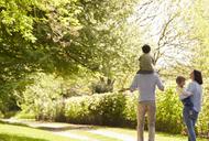 Rear View Of Family Going For Walk In Summer Countryside