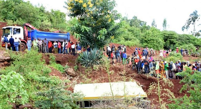 People look at the wreckage of a bus that plunged into a gorge while transporting children from Arusha to Karatu, on May 6, 2017