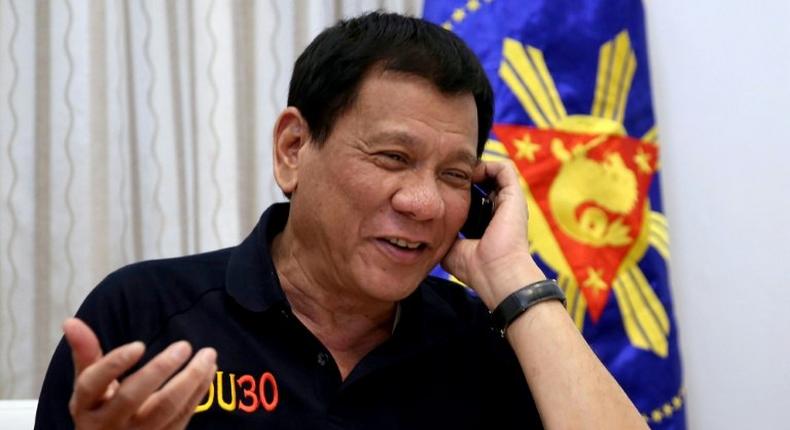 Philippines' President Rodrigo Duterte talks to US President-elect Donald Trump on the phone at Legaspi Suites in Davao City