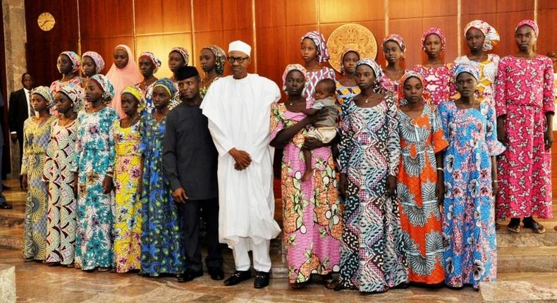 Nigerian President Muhammadu Buhari (C) poses at State House in Abuja on October 19, 2016 with the 21 Chibok girls who were released by Boko Haram the previous week