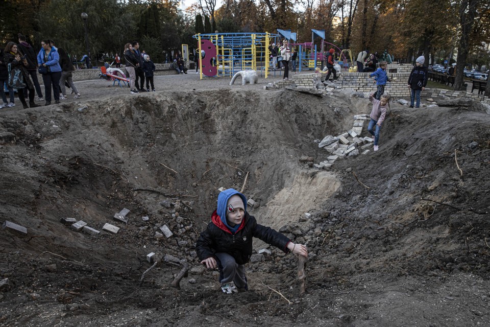 Dzieci bawią się w kraterach po pociskach w Kijowie, 16 października 2022 r.