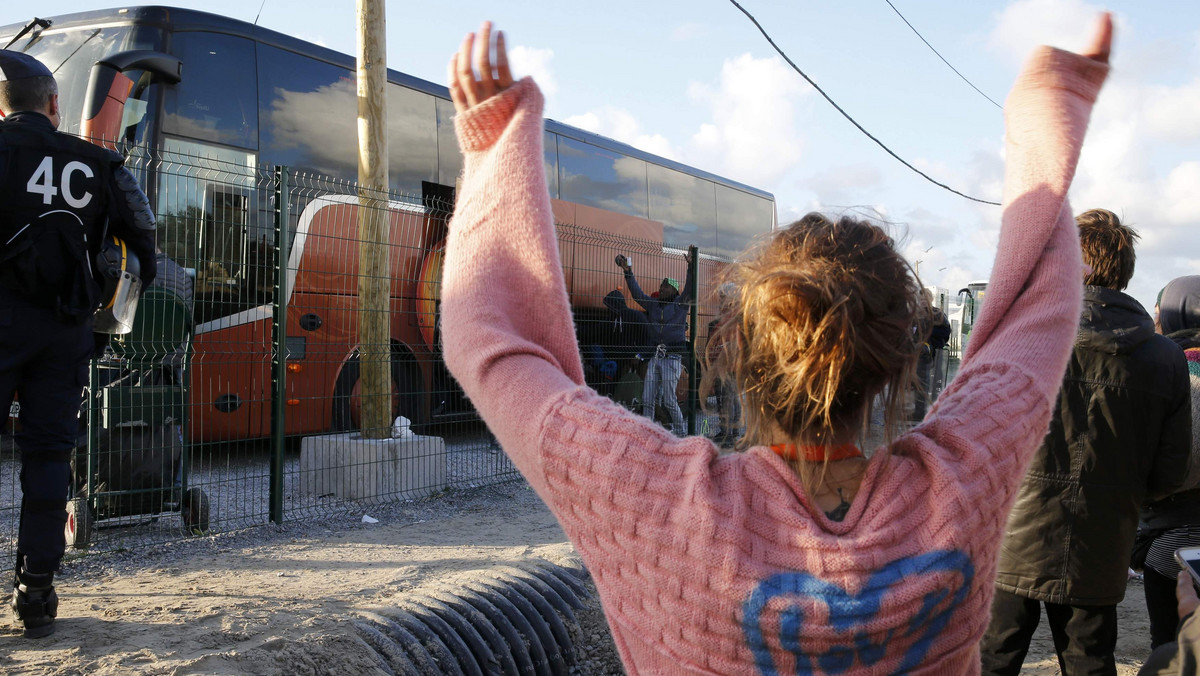 A volunteer waves to migrant minors in a bus during their transfer by French authorities to reception centres across the country at the end of the dismantlement of the camp called the "Jungle" in Calais