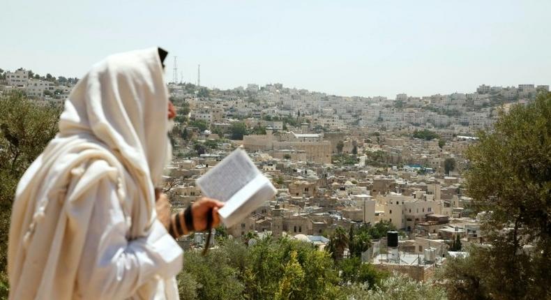 An Israeli settler stands on Palestinian land overlooking the Ibrahimi Mosque and the old city of the West Bank town of Hebron