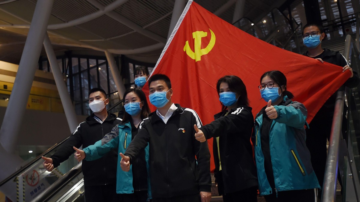 Medical workers from outside Wuhan pose for pictures with a Chinese Communist Party flag at the Wuhan Railway Station before leaving the epicentre of the novel coronavirus disease outbreak