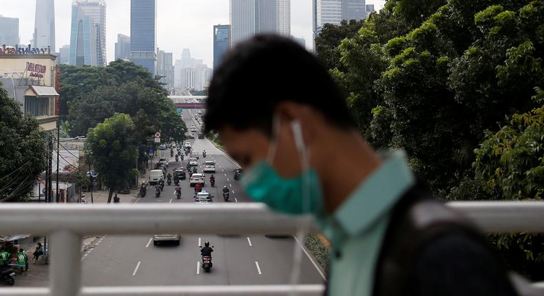 A man wearing protective mask uses his phone as he walks on a pedestrian bridge, following the outbreak of the new coronavirus in China, in Jakarta, Indonesia, February 13, 2020. REUTERS/Willy Kurniawan