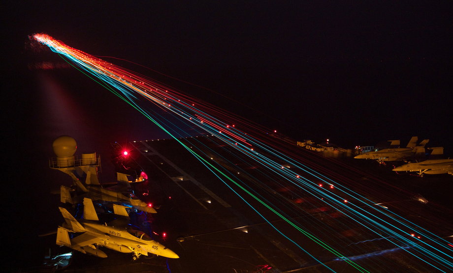 Aircraft land aboard the aircraft carrier USS Enterprise during nighttime flight operations in the Arabian Sea.