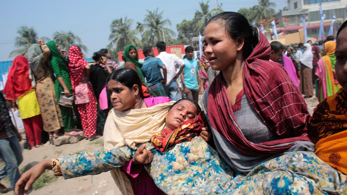 Women help a relative of a garment worker, who went missing in the Rana Plaza collapse, after she fa