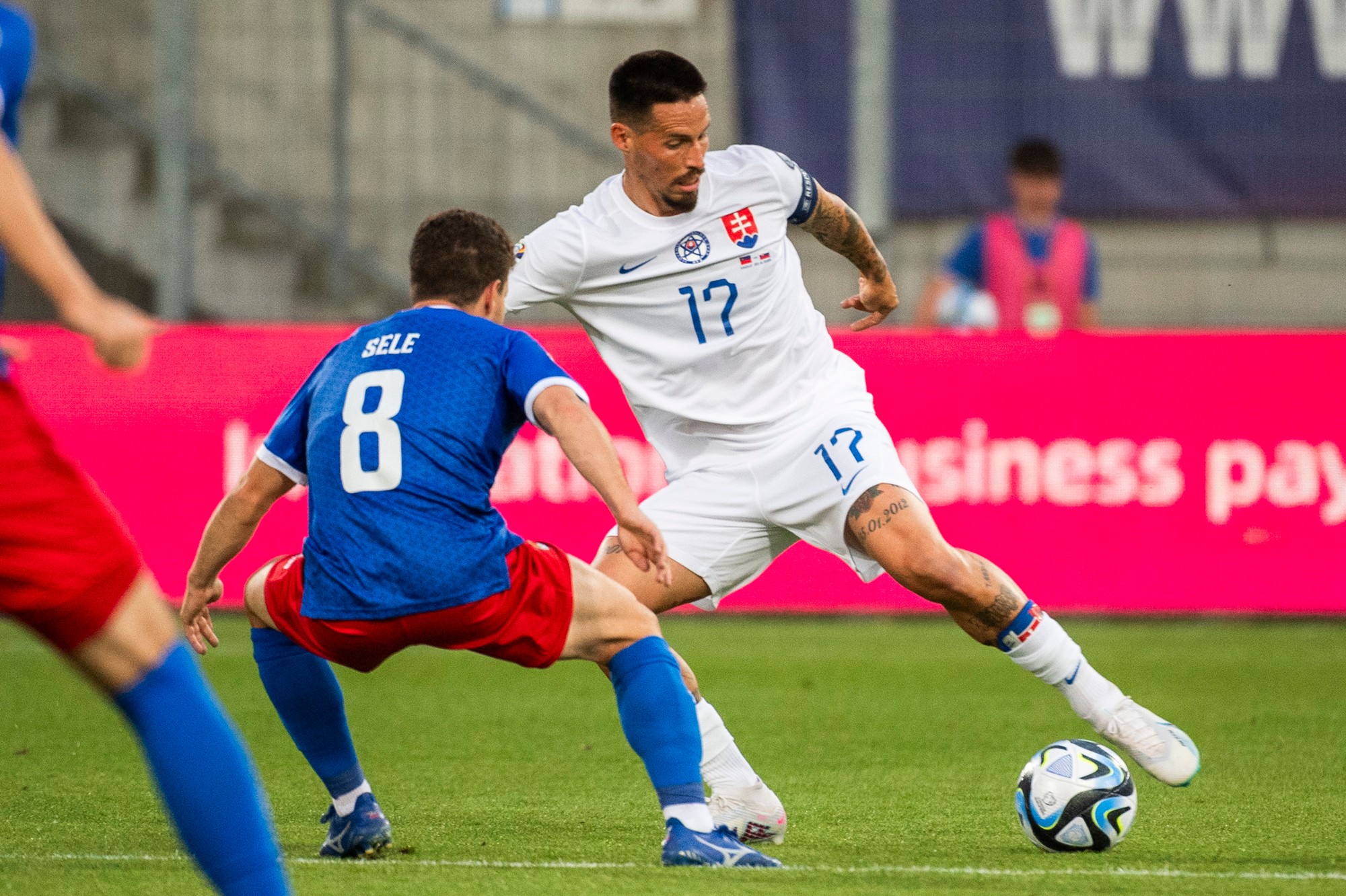 Aron Sele (Lichtenštajnsko) a kapitán Marek Hamšík (Slovensko) bojujú o loptu.