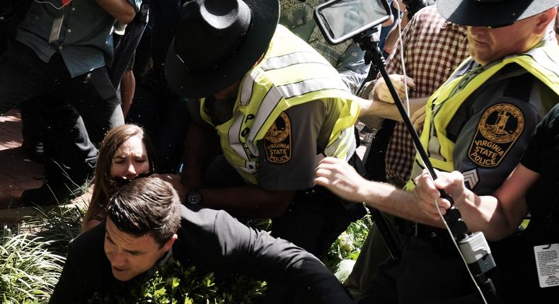 Unite The Right rally organizer Jason Kessler is helped by police after being tackled by a woman following his attempt to speak at a press conference in front of Charlottesville City Hall in Charlottesville, Virginia, August 13, 2017.