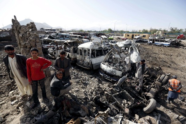 Residents stand at the site of yesterday's suicide car bomb attack on a government security building