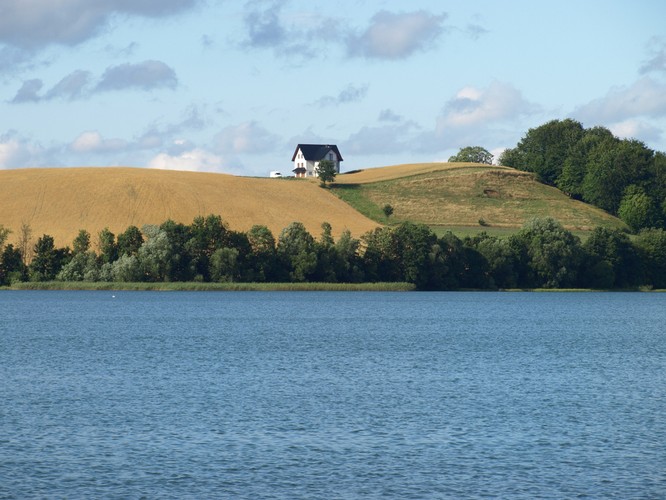 <strong>Szlak wodny „Kółko Raduńskie”</strong>
<br></br>
Trasa turystyczna przeznaczona dla miłośników rekreacji na wodzie. Wiedzie wzdłuż jezior Szwajcarii Kaszubskiej na obszarze Kaszubskiego Parku Krajobrazowego. Na odcinku od Chmielna do Krzesznej towarzyszy szlakowi wodnemu jego wariant lądowy - Droga Kaszubska, prowadząca przez Wzgórza Szymbarskie i wzdłuż brzegów „Kółka Raduńskiego”.
<br></br>
Na zdjęciu widoczne jezioro Kłodno z domem na wzniesieniu należącym do dużej i popularnej wśród turystów wsi Chmielno.
<br></br>