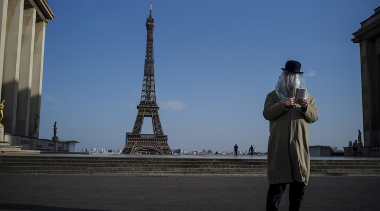 Nejlonzsákot a fejére húzva védekezik a koronavírus ellen egy férfi, aki könyvet olvas a párizsi Eiffel-torony előtt 2020. március 22-én. / Fotó: MTI/EPA/Julien De Rosa