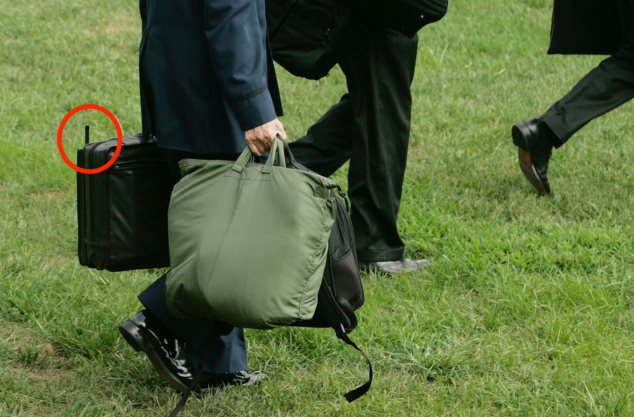 A member of the US military carries the Football behind President George W. Bush on August 2, 2005.
