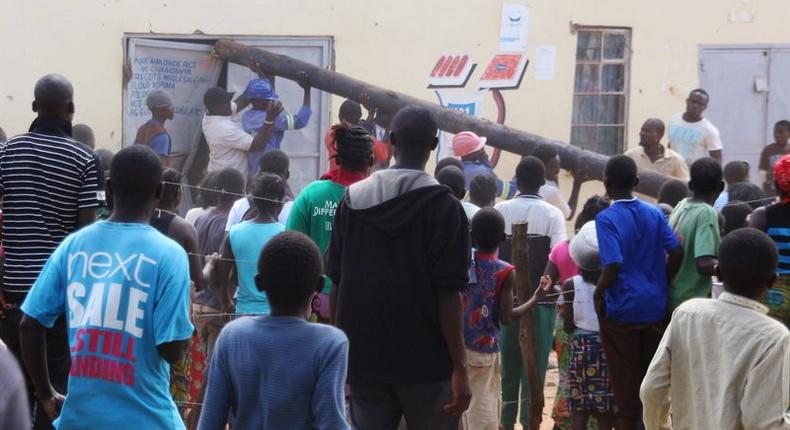 People use a pole to batter a shop doorway during clashes with police in Lusaka April 19, 2016. 