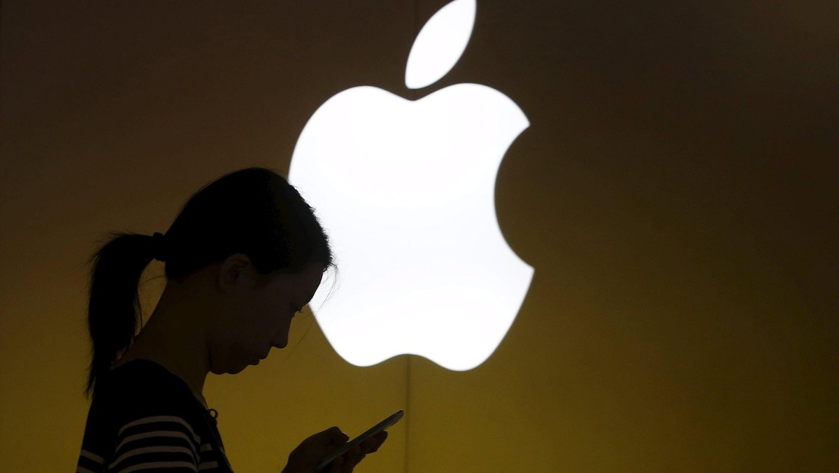 File photo of a woman looking at the screen of her mobile phone in front of an Apple logo outside an