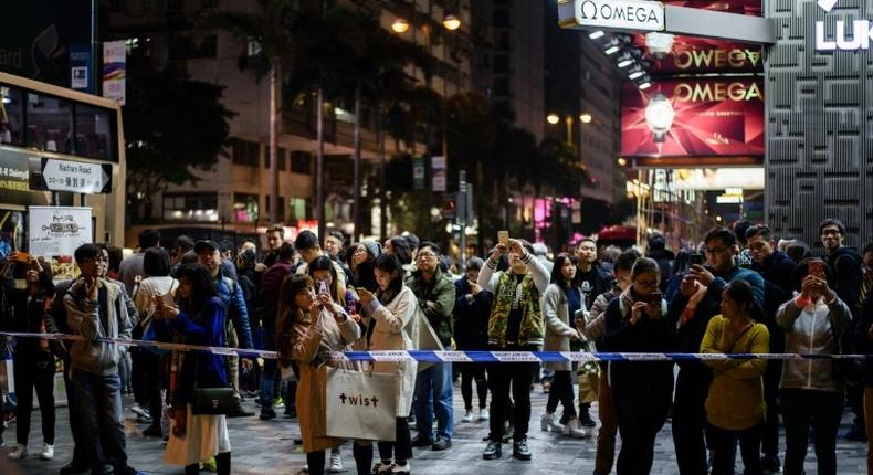 Bystanders gather behind a police cordon outside the Tsim Sha Tsui train station in the Kowloon district of Hong Kong on February 10, 2017, after a fire engulfed a subway train