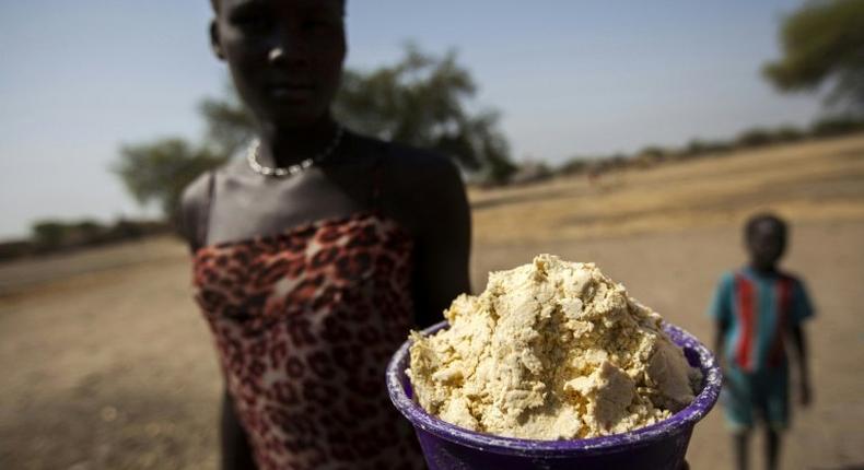 A woman holds out a bowl of partially boiled maize in Ngop in South Sudan's Unity State on March 10, 2017