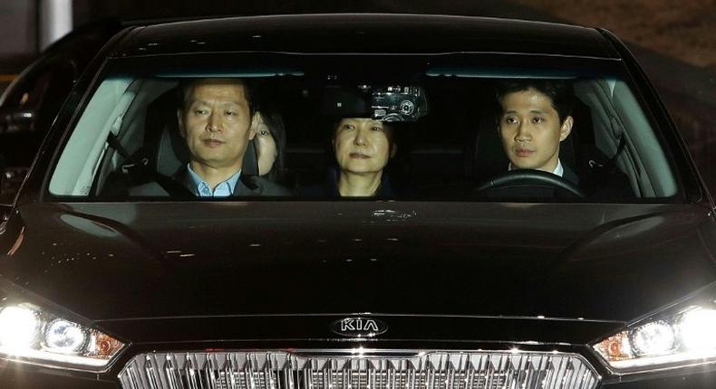 Ousted South Korean President Park Geun-hye (C), leaves the prosecutors' office in a car as she is transferred to a detention house early on March 31, 2017 in Seoul