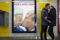 A couple stands next to a poster depicting Dutch politician Geert Wilders and Russian President Vlad